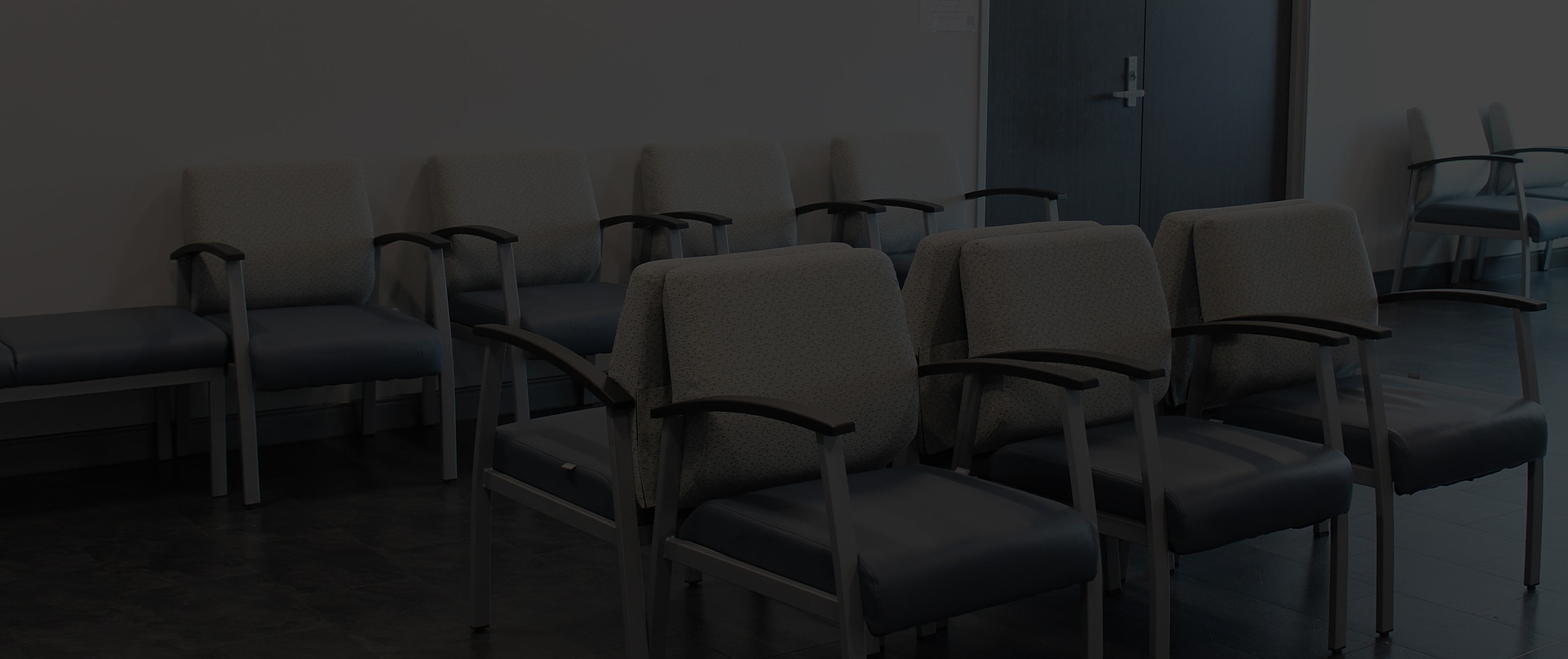 Empty waiting room with gray chairs arranged neatly.