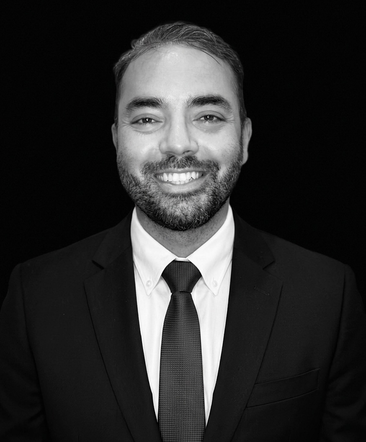 Smiling man in suit against black background.
