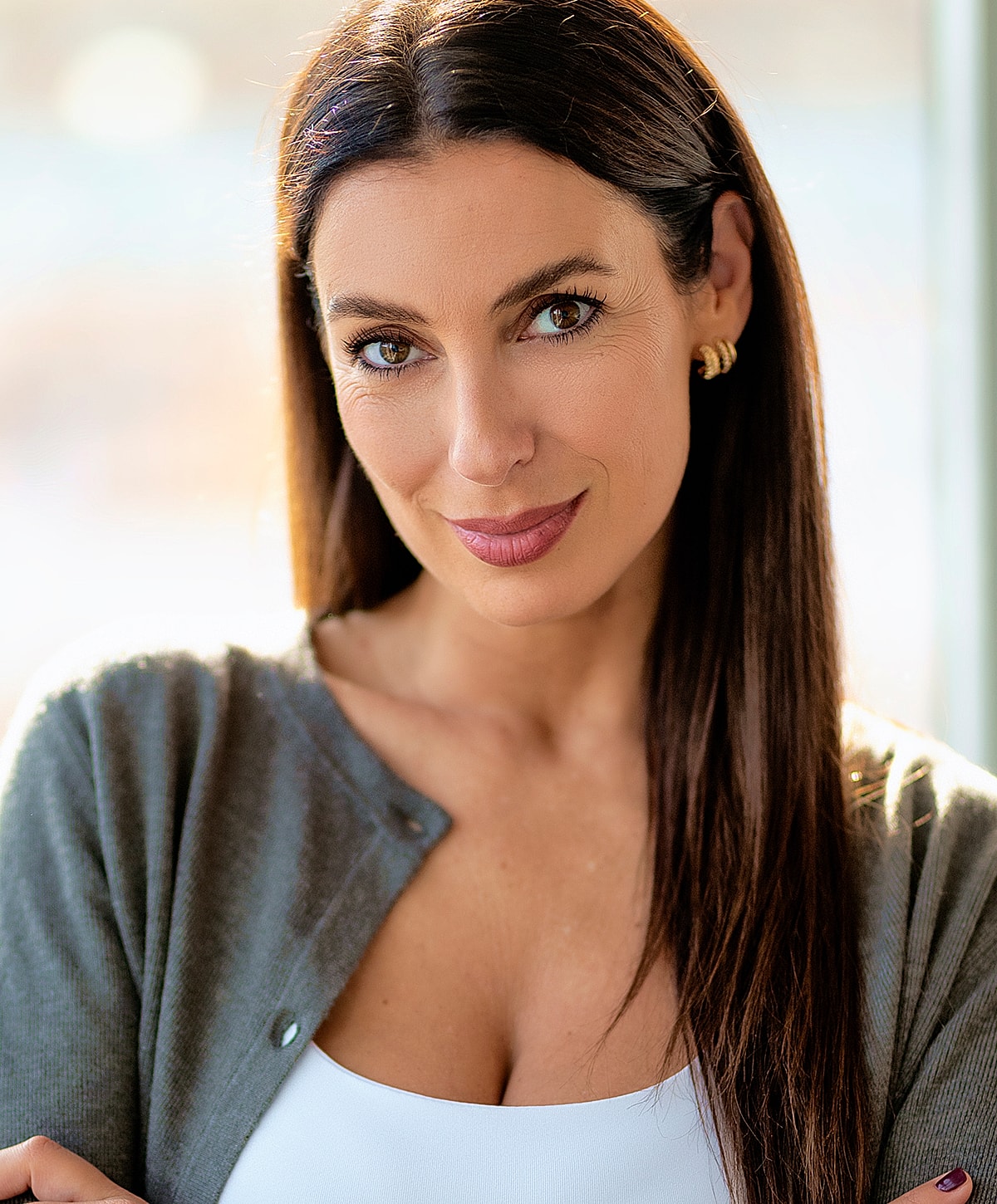 Smiling woman with long hair and cardigan.