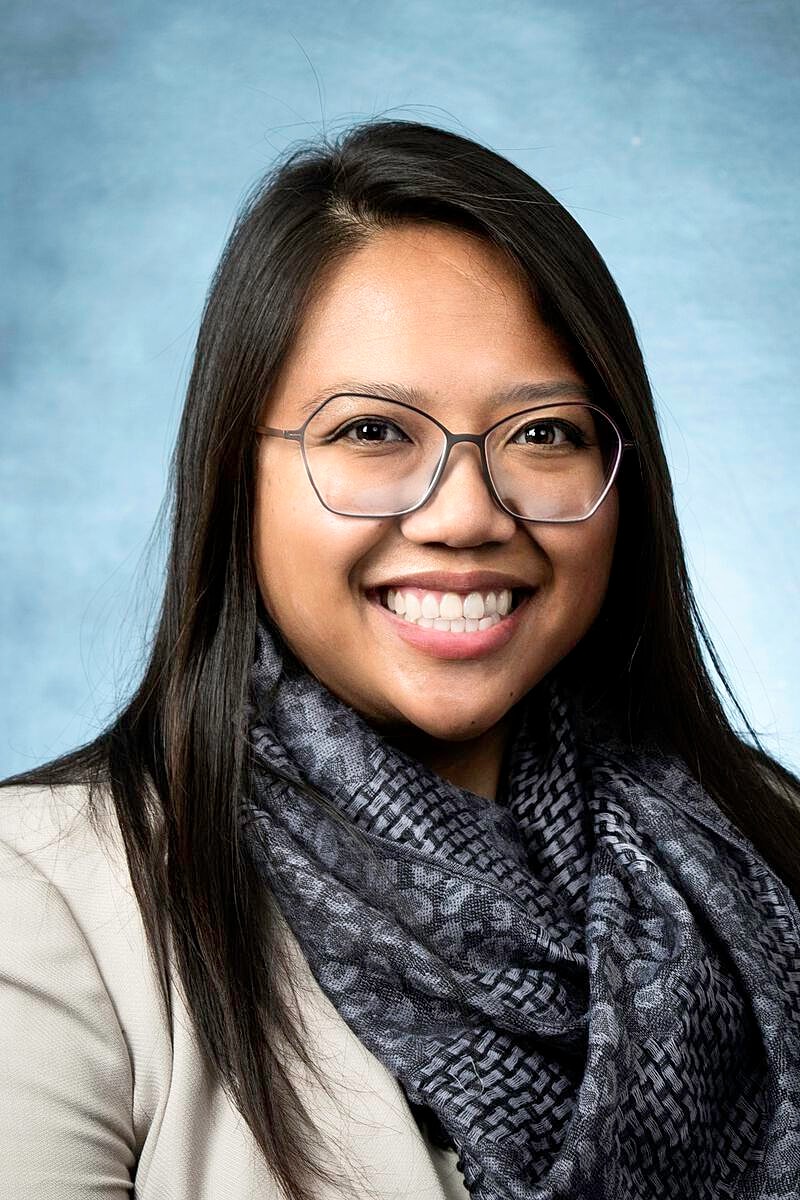 Smiling woman with glasses and scarf.