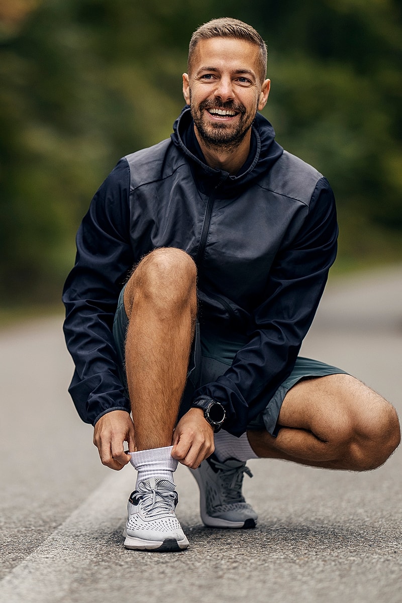 Man tying shoelaces in athletic attire outdoors