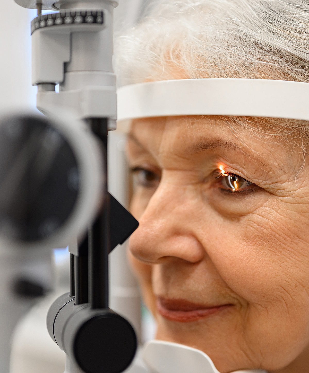 Eye exam with elderly woman using equipment.