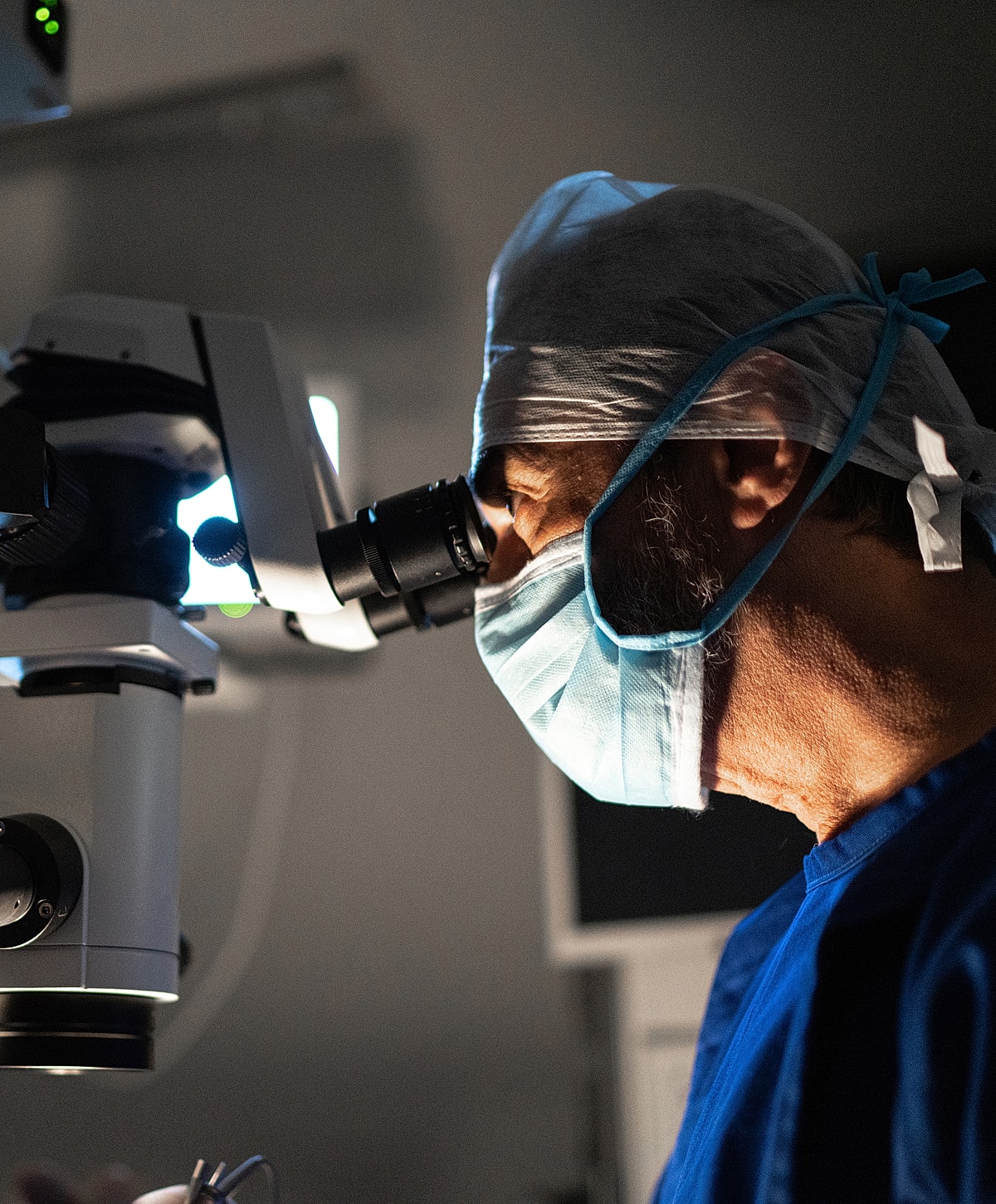 Surgeon using a microscope in a medical setting.