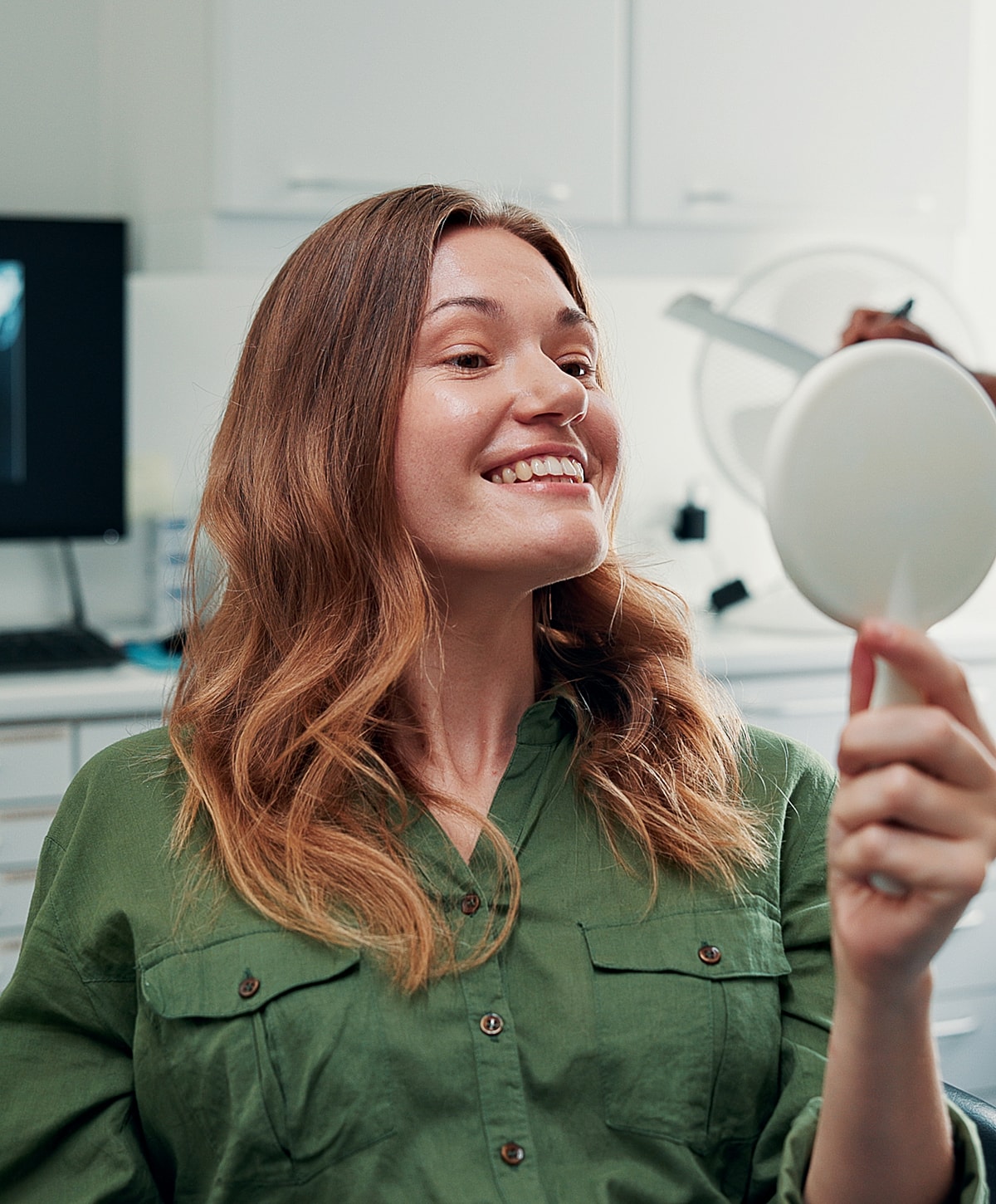 Woman smiling in mirror at dental office.
