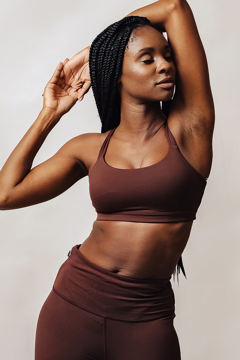 Woman in activewear posing confidently against backdrop.