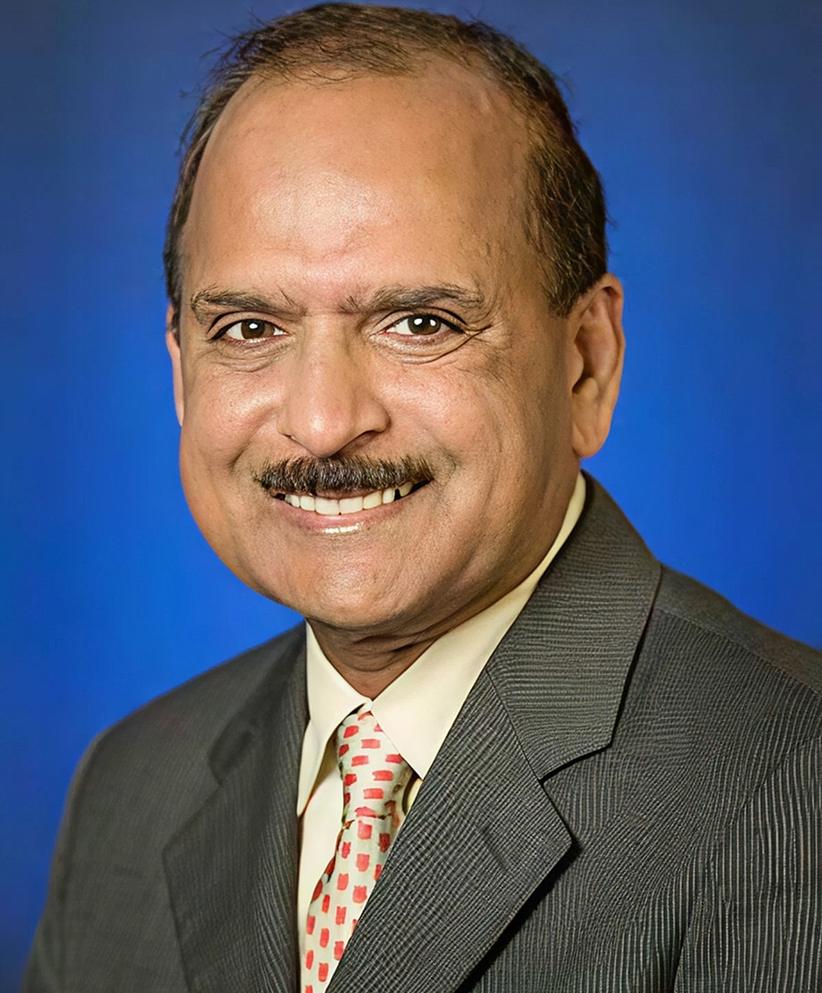Smiling man in a suit against blue background.