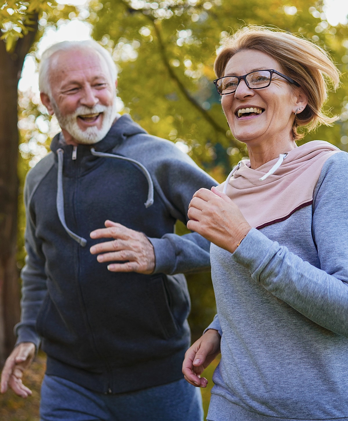 Elderly couple jogging together in nature.