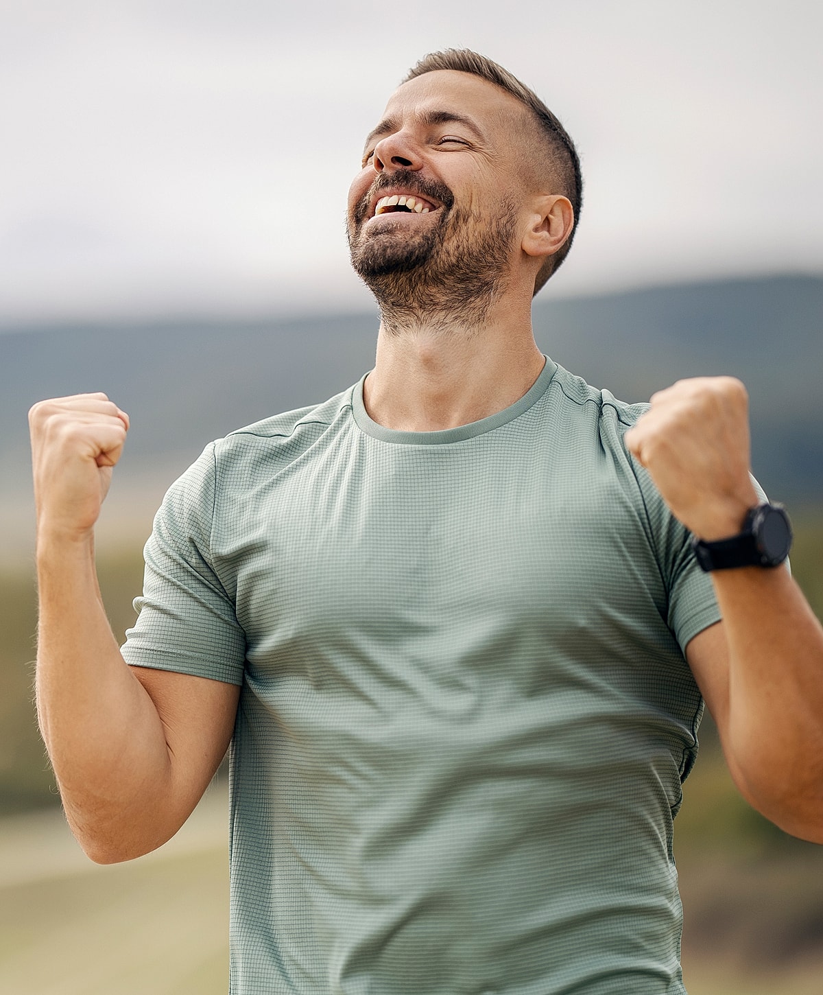 Happy man celebrating outdoors with raised fists.