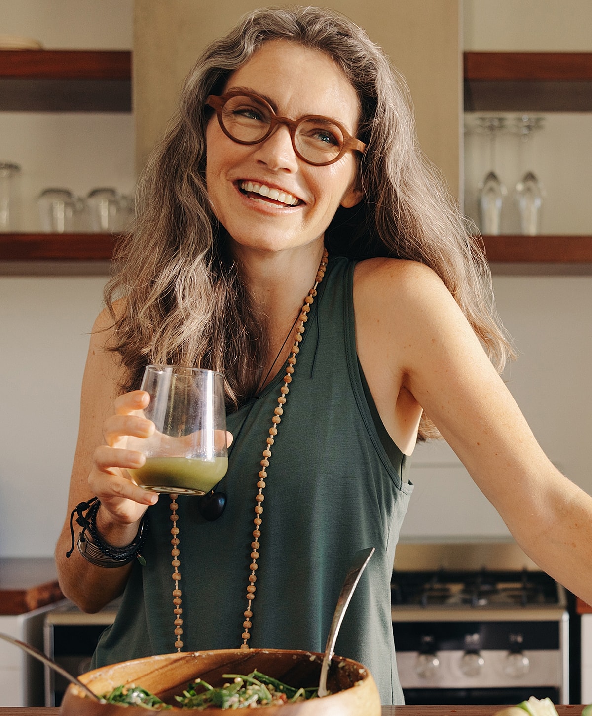 Smiling woman holding drink in a kitchen.
