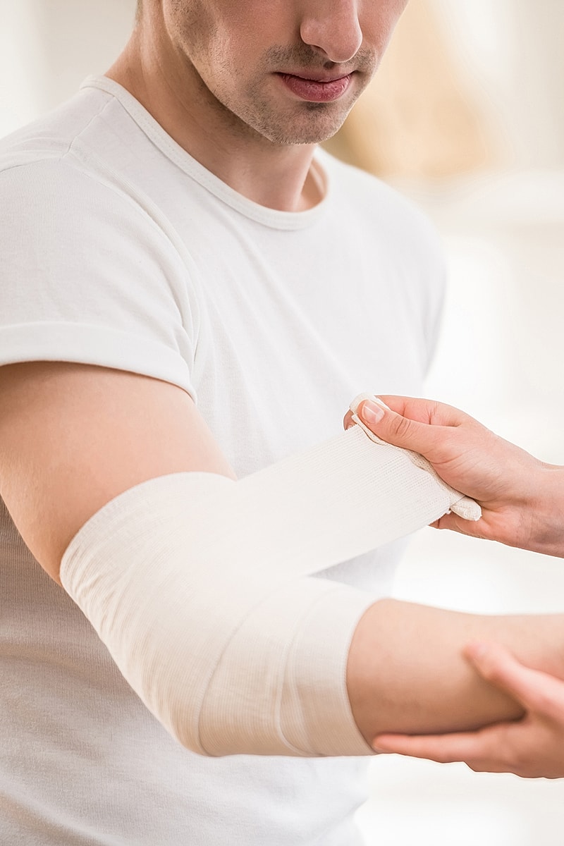 Applying a bandage to an injured arm.