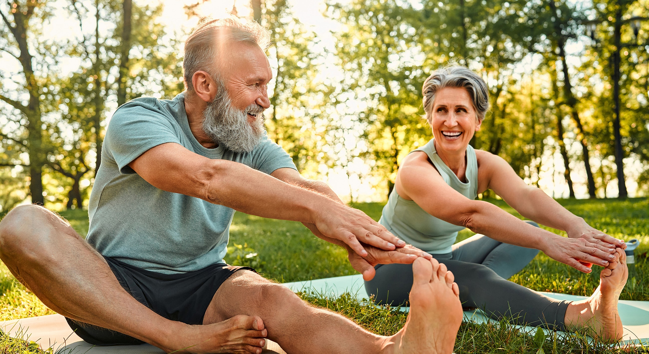 Older couple stretching together in a park.