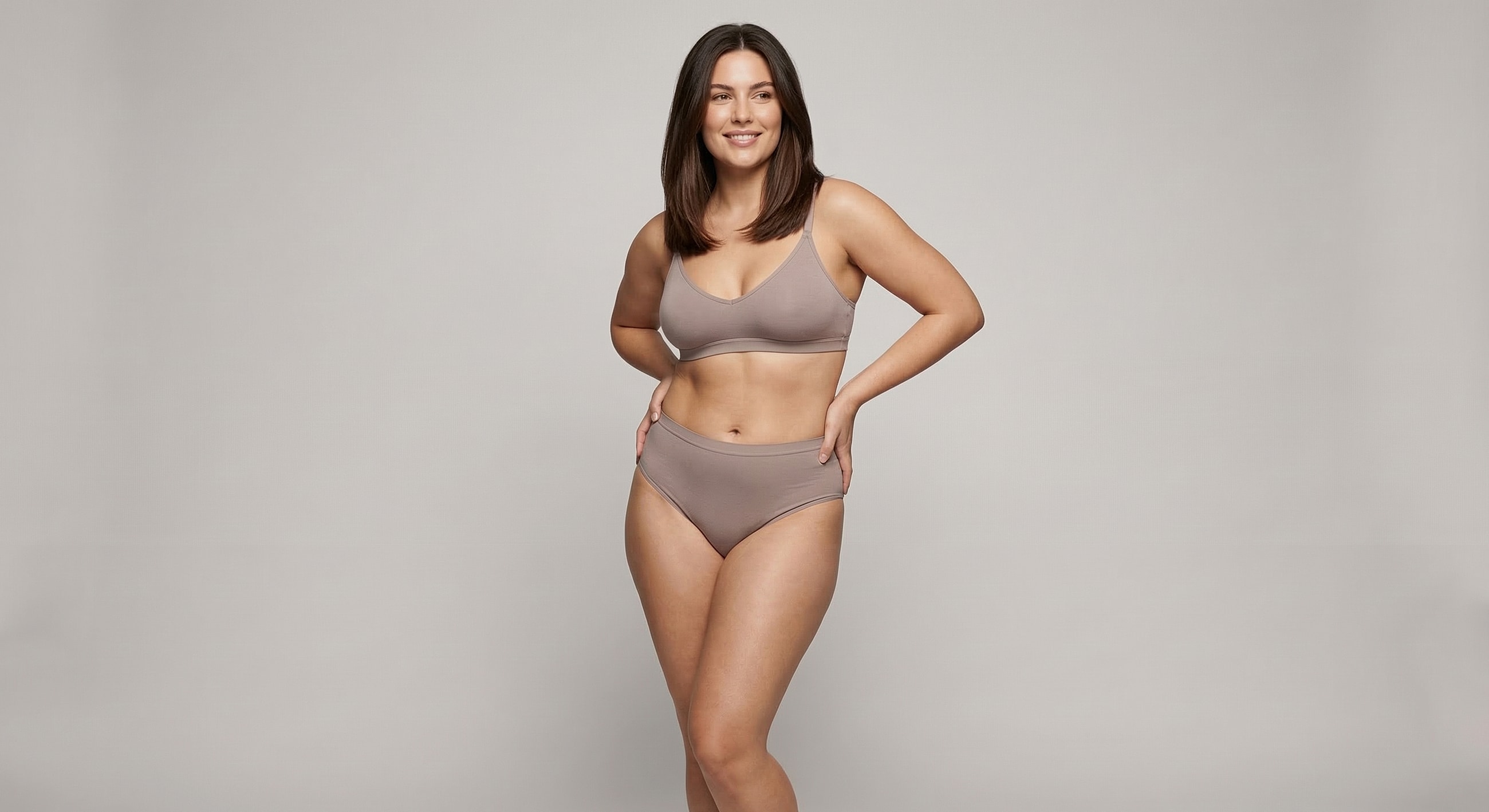 Model in stylish lingerie against plain background.