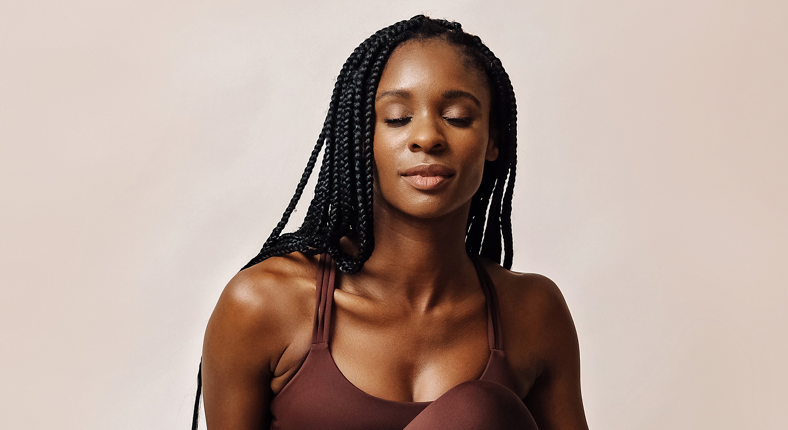 Woman with braids in yoga pose, serene expression.