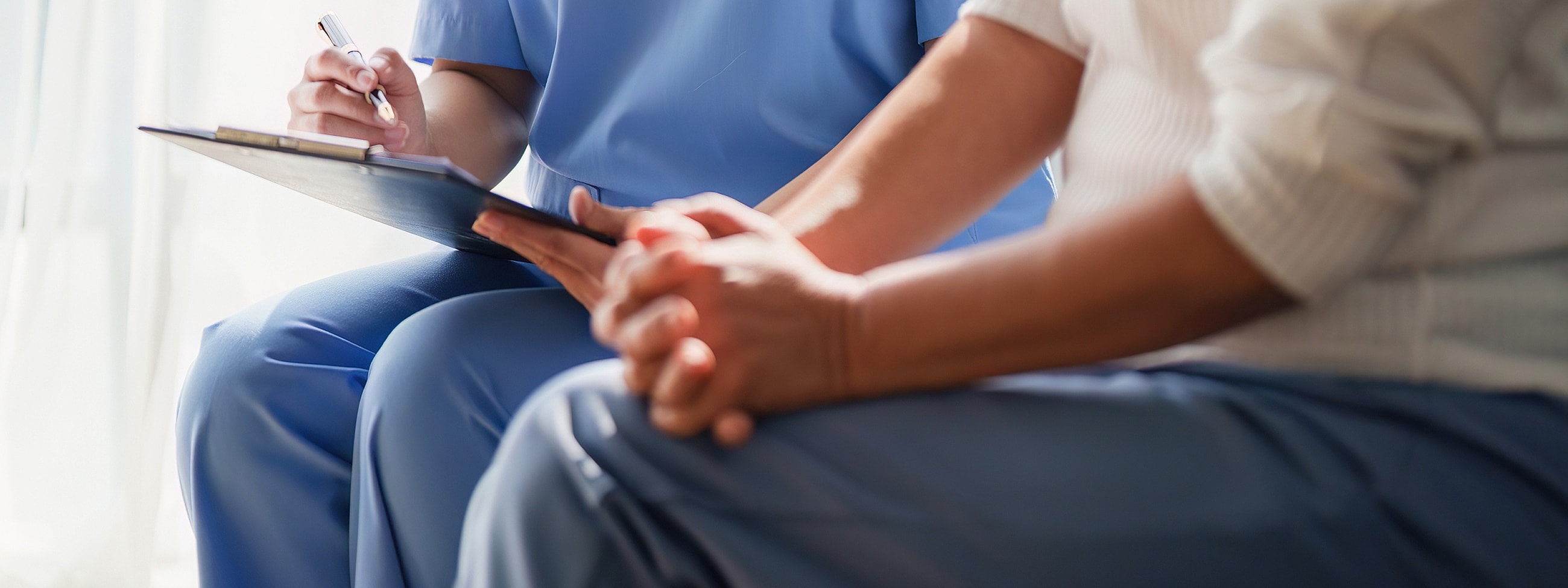 Nurse taking notes during patient consultation.