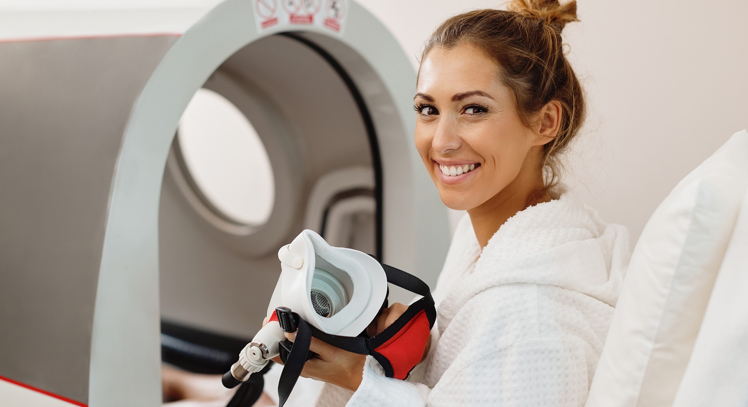 Woman smiling in spa setting, holding equipment.
