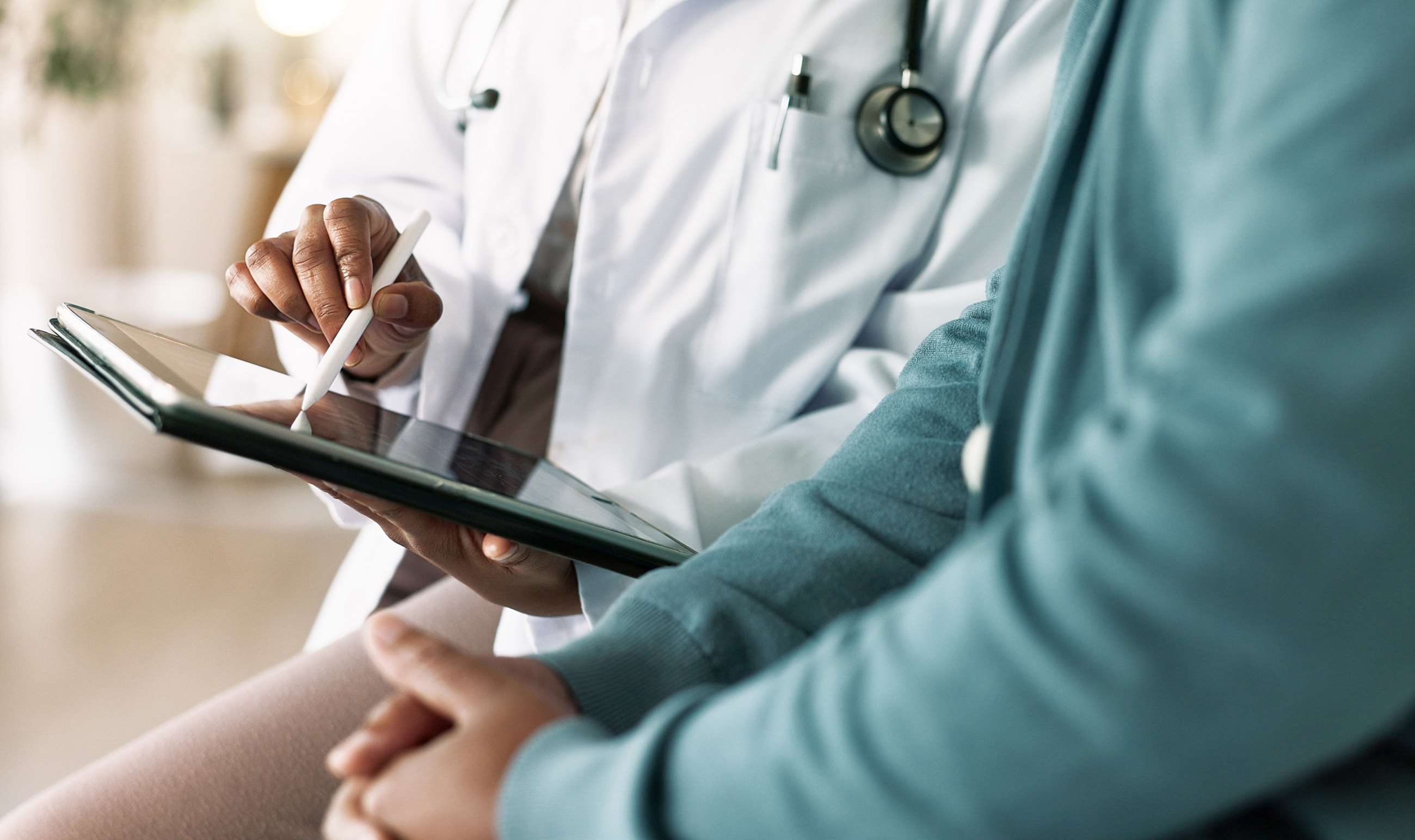 Doctor consulting with patient using tablet device.