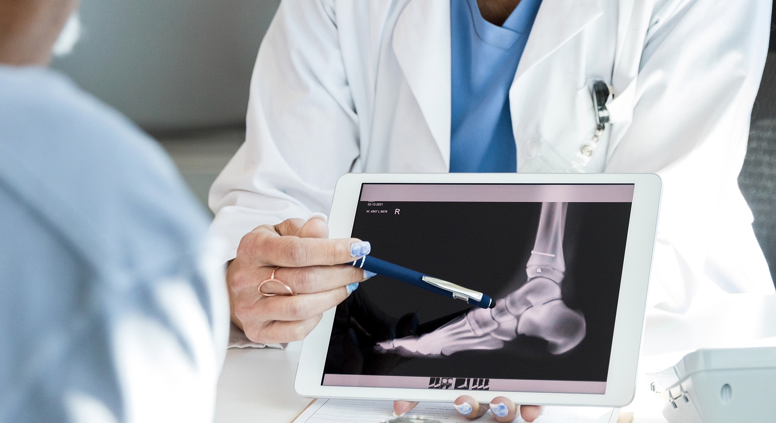 Doctor showing X-ray on tablet to patient.