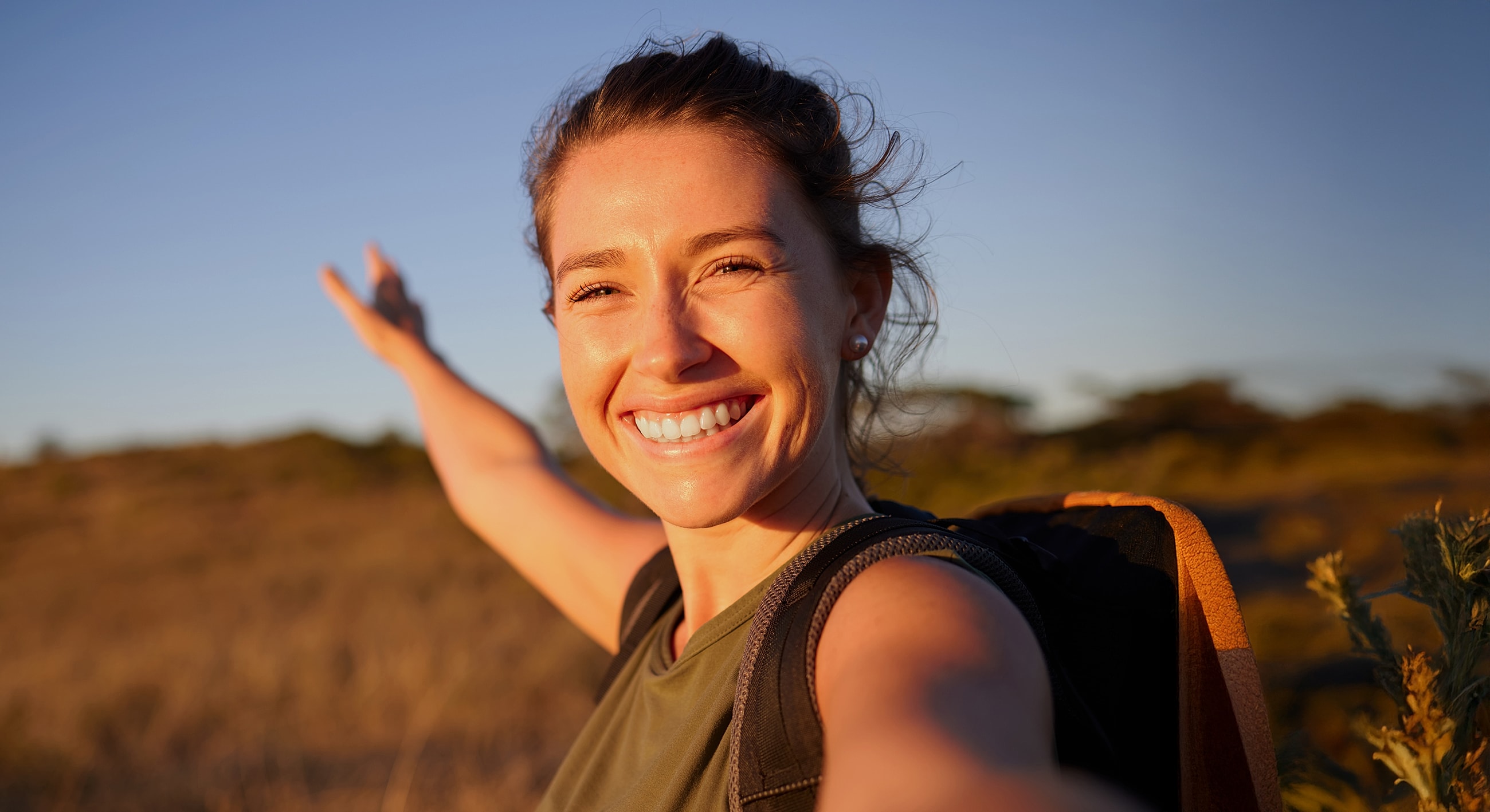 Smiling hiker enjoying sunset outdoors.